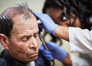 An older man receives a check-up at a clinic.